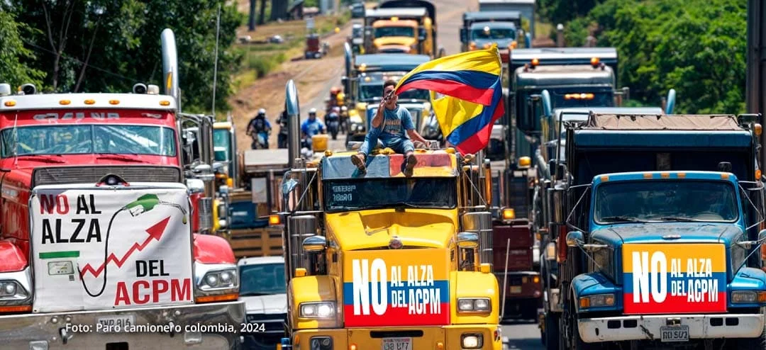 Camiones en protesta por el alza del precio del ACPM en Colombia, con pancartas y una bandera colombiana.