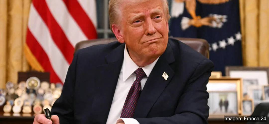 Donald Trump sentado en su escritorio firmando documento en la Casa Blanca