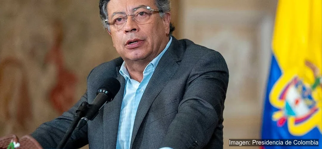 Gustavo Petro hablando frente a micrófono con la bandera de Colombia al fondo durante discurso oficial