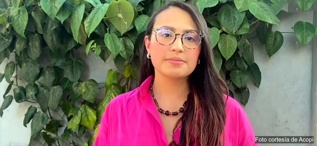María Alejandra Osorio posa con camisa fucsia frente a un muro cubierto de hojas verdes