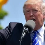 Donald Trump con micrófono y el puño alzado durante un discurso público sobre política comercial