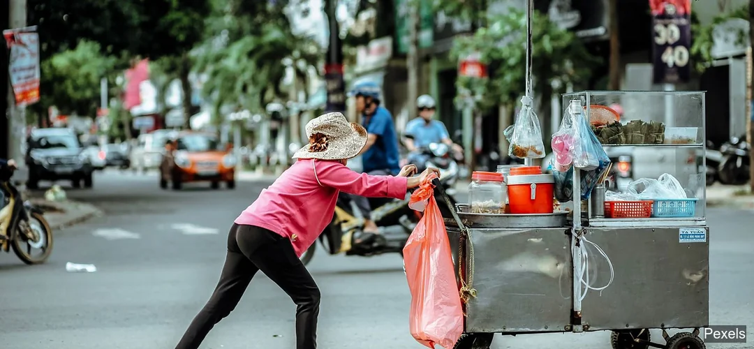 Vendedora ambulante trabaja en calle urbana con carrito de alimentos
